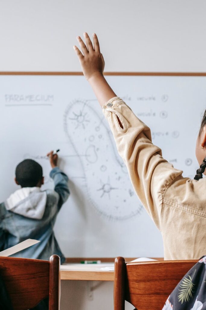 Students attentively participate in a science lesson with a teacher at the whiteboard.