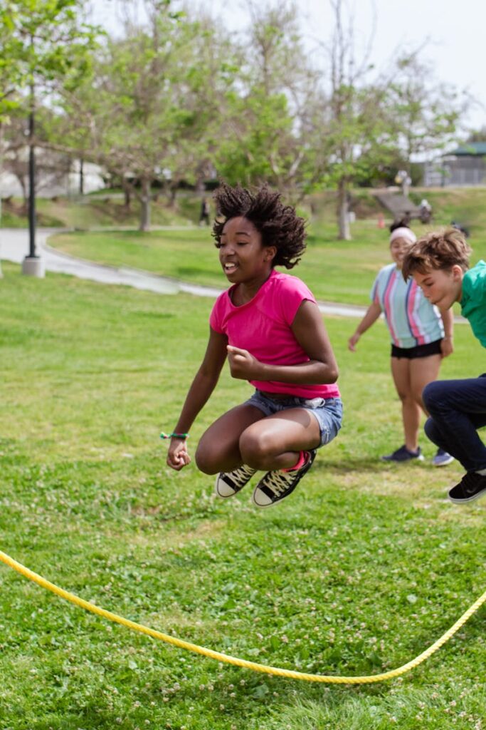 Children enjoying a vibrant day playing jump rope outdoors at summer camp.